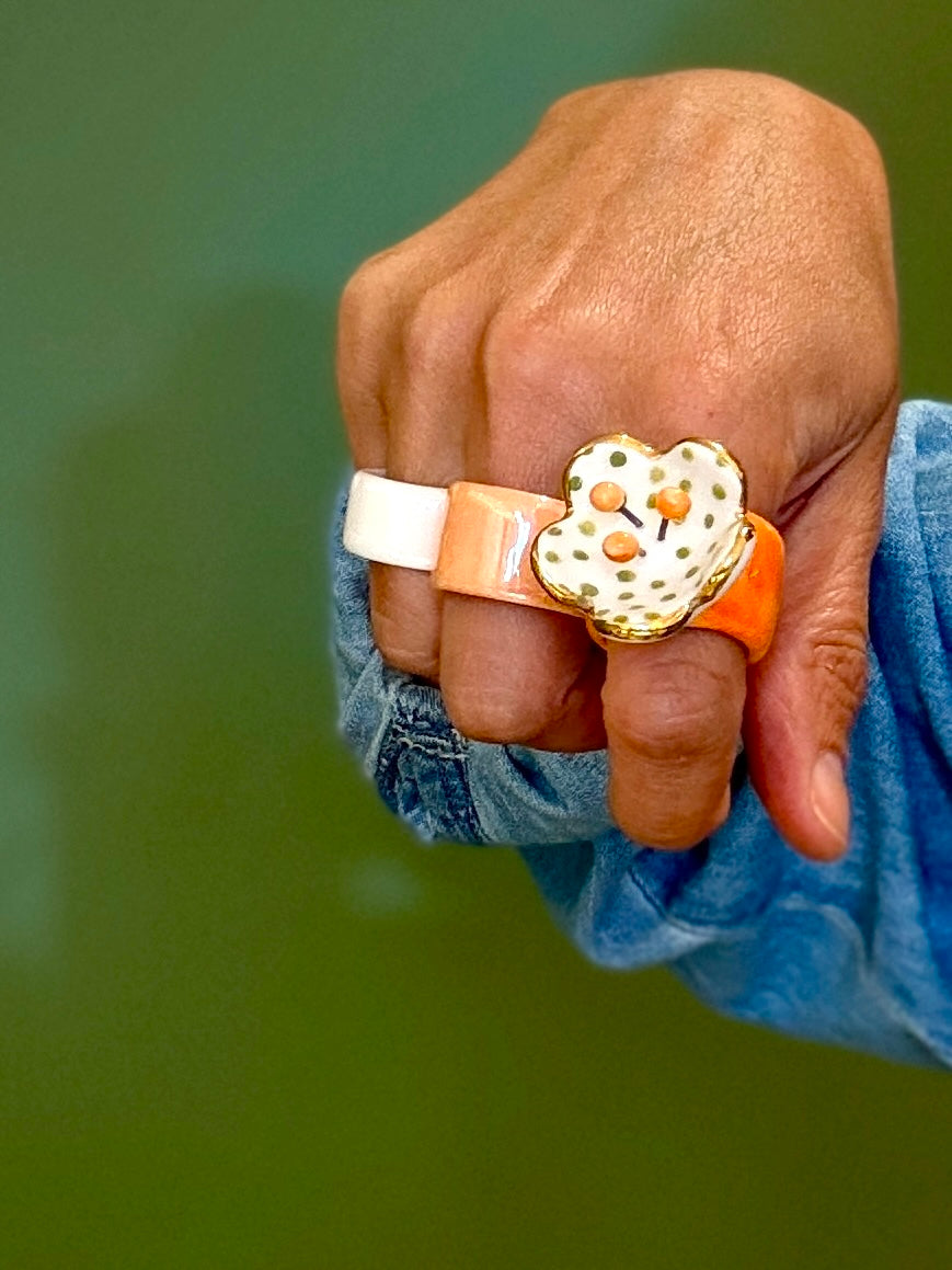 Hand wearing a ring with a heart-shaped design on a green background