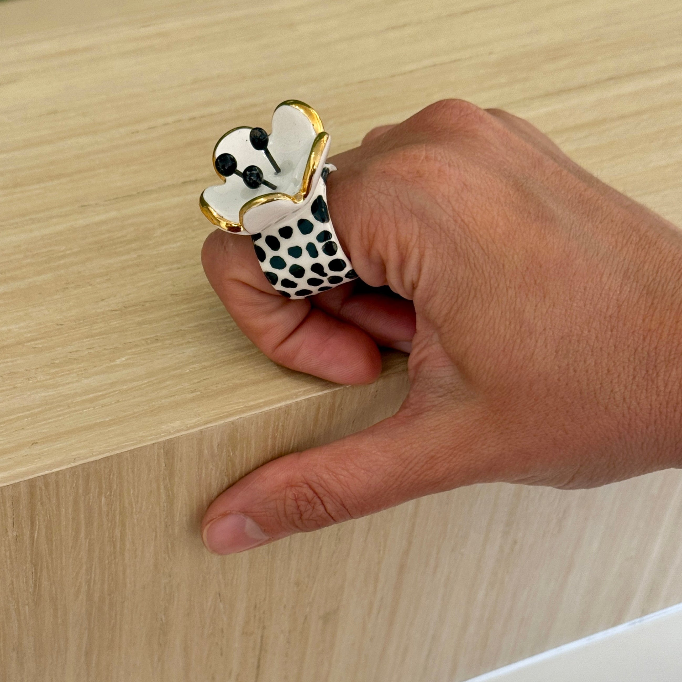 Hand holding a decorative paw-shaped object on a wooden surface