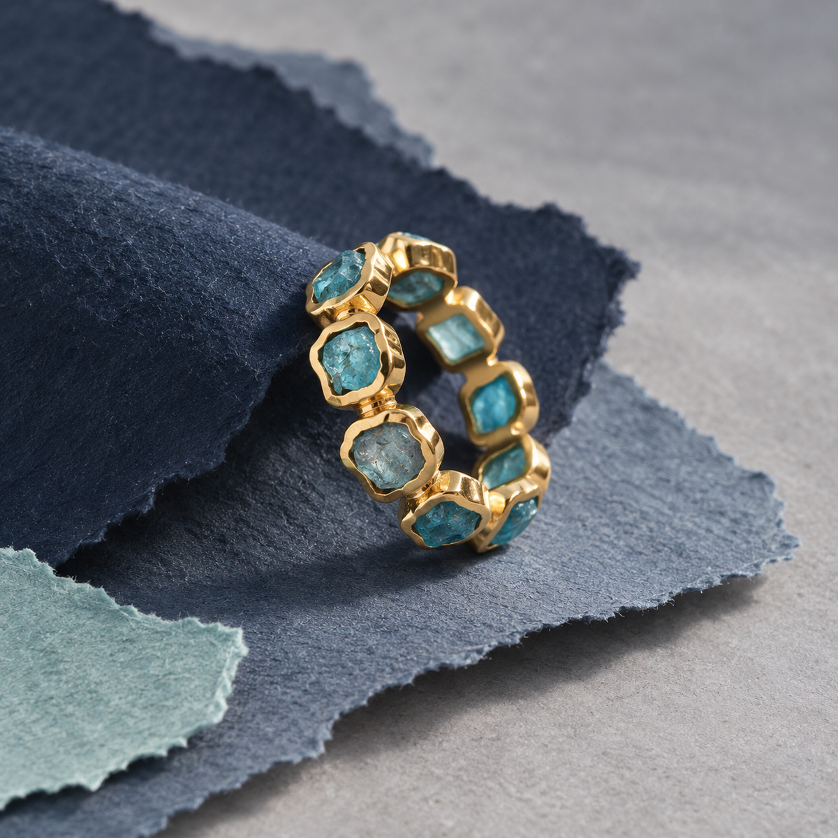Deformed Apatite Ring staged with blue handmade paper